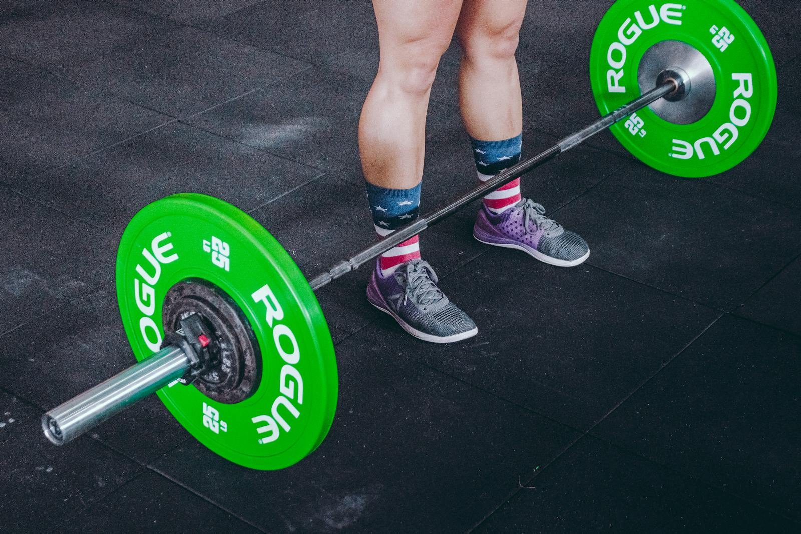 Focused view of legs and barbell at the gym, emphasizing strength and fitness.
