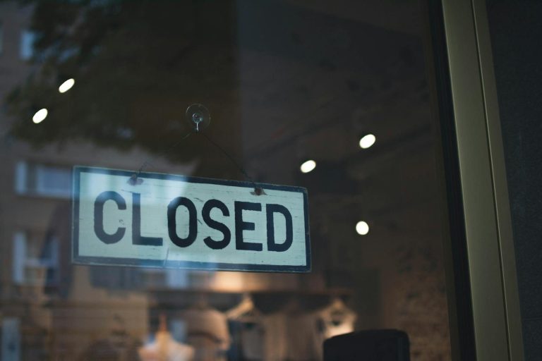 A closed sign hangs on a glass window of a modern urban storefront.