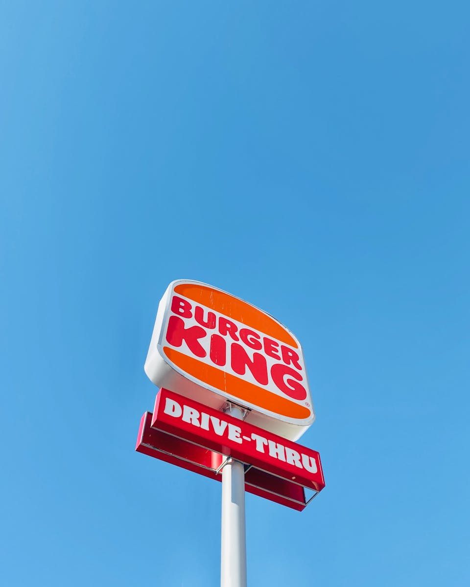 Burger King drive-thru sign with clear sky background. Vibrant colors and minimalistic composition.